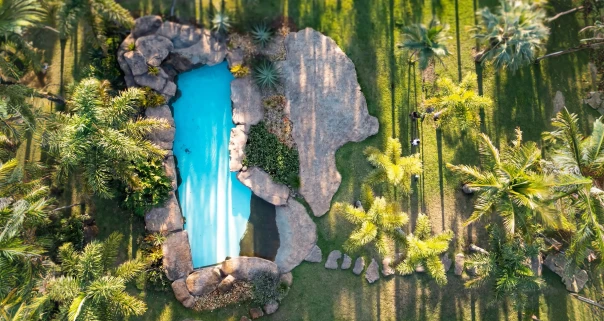 Piscina artificial integrada ao paisagismo entre pedras e vegetação