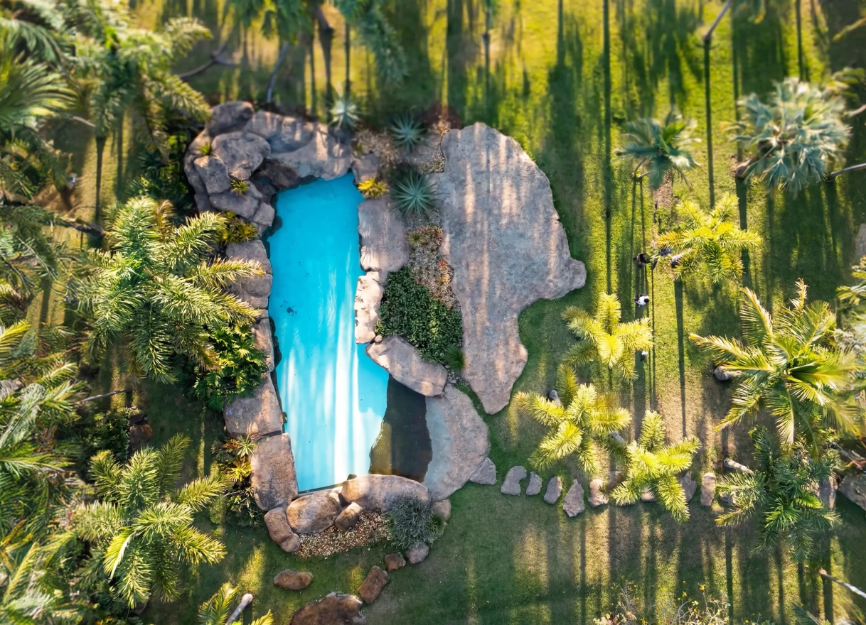 Piscina artificial com cascata e fonte entre rochas
